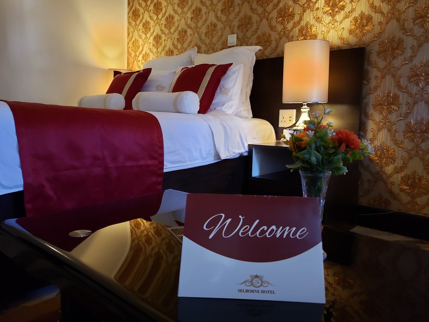 Selborne guest room with burgundy accents and a welcome card